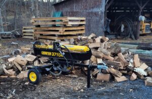 Log splitter in front of a pile of logs. 