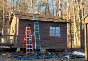 Side of cabin at camp with two ladders propped against it. 